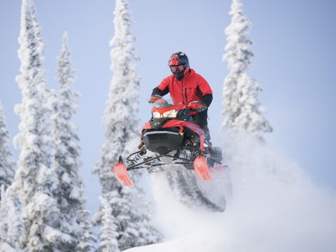 Lynx Rave RE snøscooter i aksjon med fører som kjører over snødekt terreng